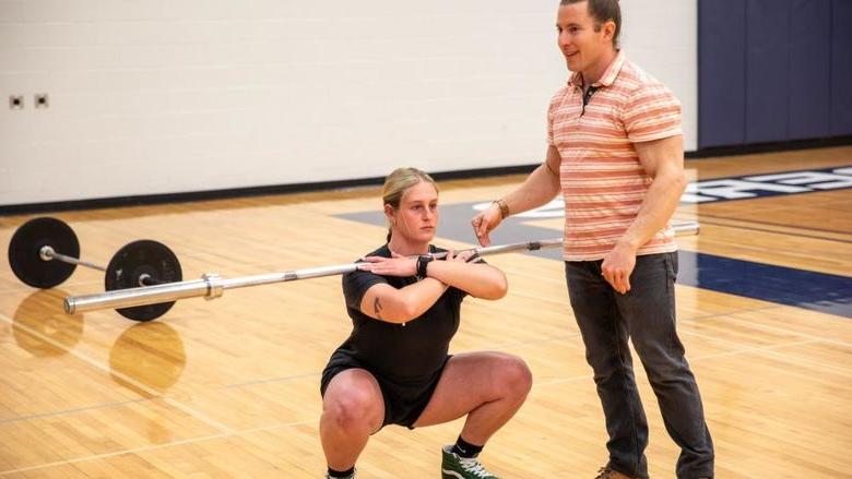 Student squats with lifting bar 